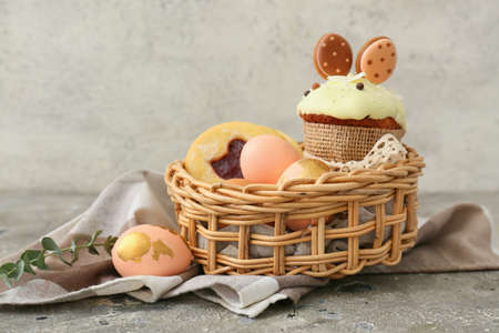 Gift basket with painted Easter eggs, cookies and cake on table