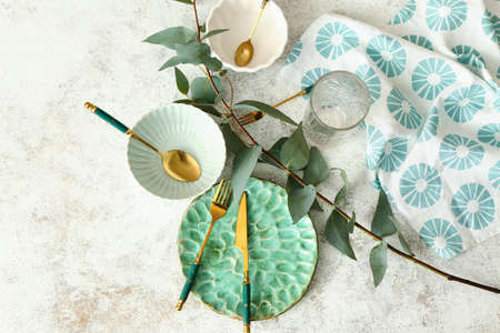 Stylish table setting and green plant branch on light background