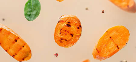 Flying grilled carrot pieces with spices on light backgroundの写真素材