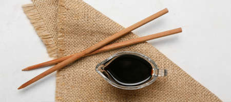 Gravy boat of soy sauce and chopsticks on white backgroundの写真素材
