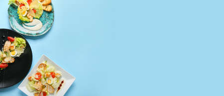 Plates of fresh Caesar salad on blue background with space for text
