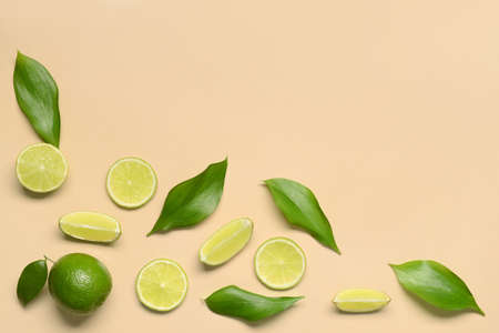 Fresh juicy limes and leaves on beige background