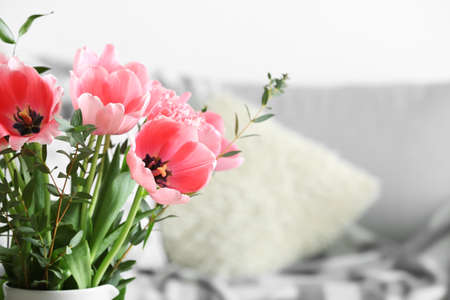Vase with pink tulips in light living room, closeup