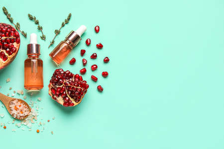 Bottles of natural serum, spoon with sea salt, pomegranate and thyme on blue backgroundの写真素材