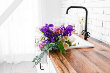 Sink with beautiful flowers on counter in kitchen, closeupの写真素材