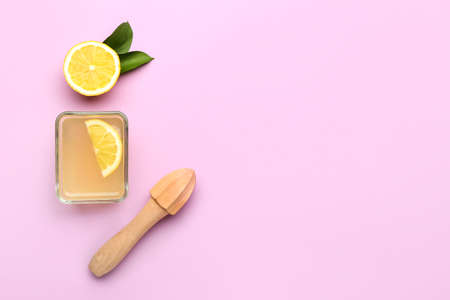 Composition with fresh lemon juice and wooden juicer on color background