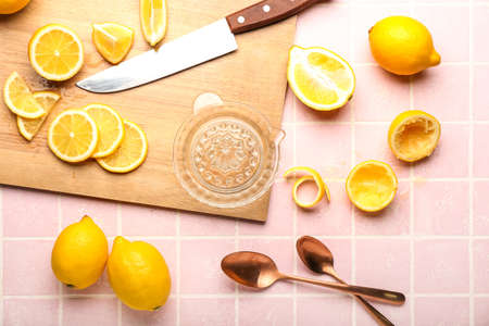 Composition with ripe lemons and juicer on color tile