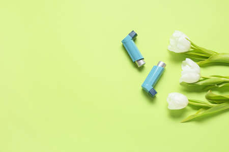 Inhalers and tulip flowers on green background