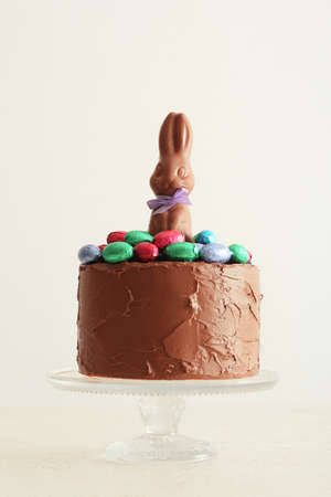 Tasty Easter cake decorated with chocolate bunny and eggs on light backgroundの写真素材