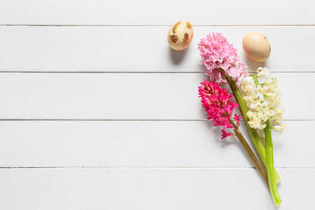 Beautiful hyacinth flowers and Easter eggs on light wooden background