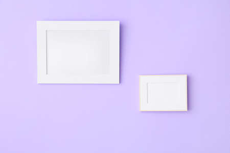 Blank photo frames hanging on lilac wall