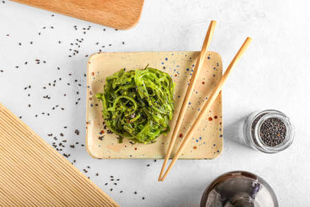 Plate with healthy seaweed salad on light background