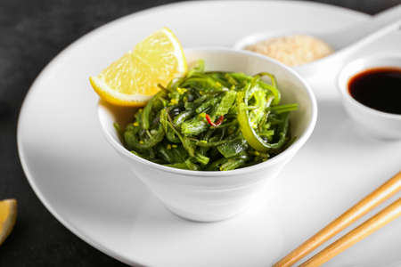 Bowl with healthy seaweed salad on dark background