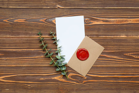 Envelope with card and eucalyptus branches on wooden background