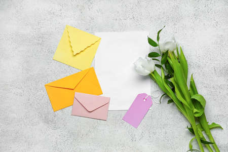 Envelopes with blank card and beautiful flowers on light backgroundの写真素材