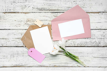 Envelopes with cards and flowers on white wooden backgroundの写真素材