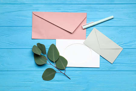 Envelopes with blank card, pen and eucalyptus branch on blue wooden backgroundの写真素材