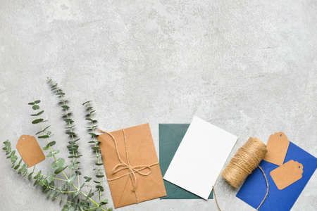 Envelopes with blank card, eucalyptus branches, tags and rope on light backgroundの写真素材