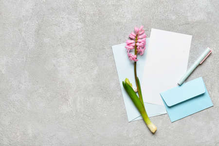 Envelopes with blank card, flowers and pen on light backgroundの写真素材
