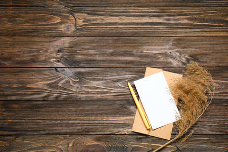 Envelope with blank card, pen and pampas grass on dark wooden backgroundの写真素材