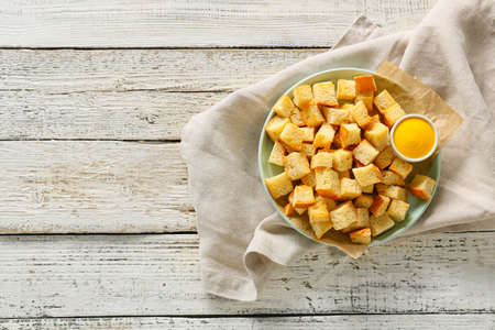 Plate of crunchy croutons and tasty sauce on wooden table, top viewの写真素材