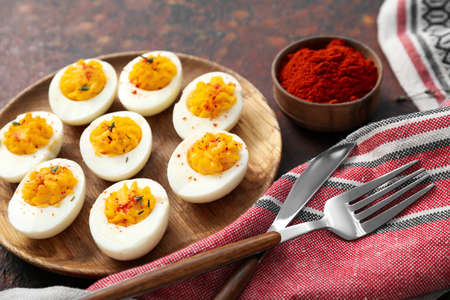 Plate with stuffed eggs, paprika, cutlery and napkin on grunge background, closeup. easter...