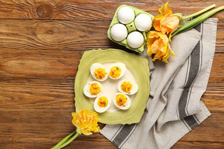 Plate and holder with eggs, flowers and napkin on wooden background. easter celebration