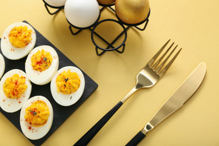 Board and holder with stuffed eggs on yellow background. easter celebrationの写真素材