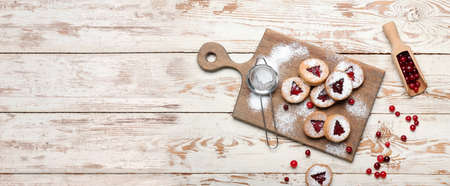 Board with tasty Linzer cookies, cranberry and powdered sugar on wooden background with space for textの写真素材