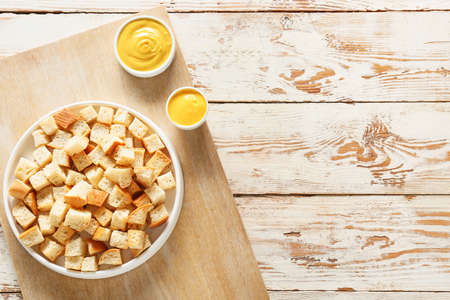 Bowl with croutons and sauces on light wooden background