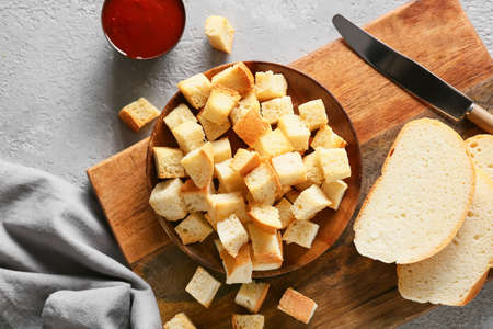 Board with croutons, bread slices, knife and sauce on light backgroundの写真素材