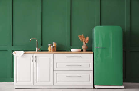 Kitchen counter with sink and retro fridge near green wallの写真素材
