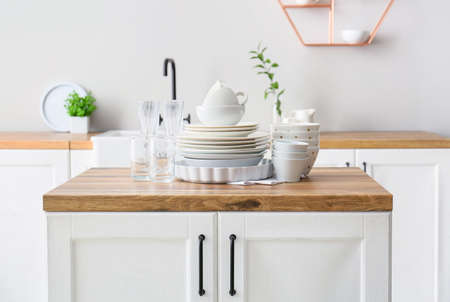 Beautiful dinnerware on wooden counter in light kitchenの写真素材