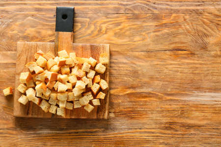 Chopping board with tasty croutons on wooden backgroundの写真素材