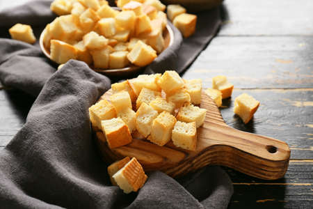 Board with tasty croutons and napkin on dark wooden background, closeupの写真素材