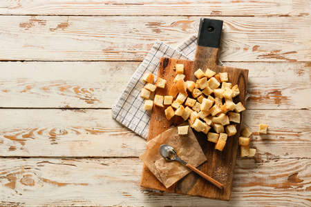 Board with croutons, spoon, parchment paper and napkin on light wooden backgroundの写真素材