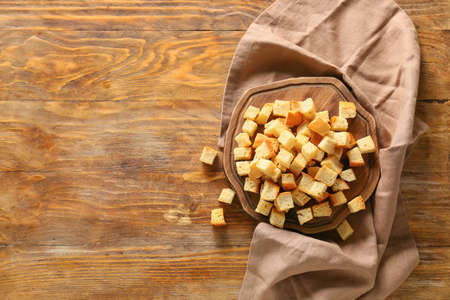Board with tasty croutons and napkin on wooden backgroundの写真素材
