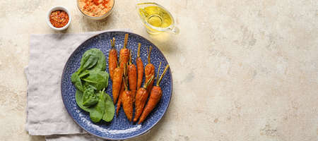 Plate with tasty baked carrots and spinach on grunge background with space for textの写真素材