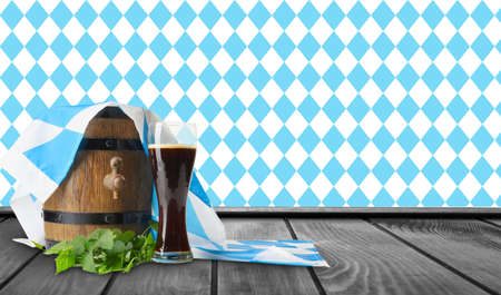 Wooden barrel and glass of fresh beer with Bavarian flag on table. Oktoberfest celebrationの写真素材