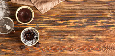 Ramekins with tasty lava cakes on wooden background with space for text