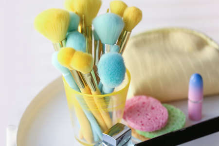 Holder with colorful makeup brushes on table in room, closeupの写真素材