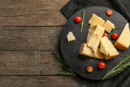 Board with pieces of tasty Parmesan cheese and tomatoes cherry on wooden backgroundの写真素材