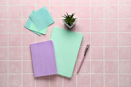 Notebooks, sticky papers, succulent and pen on pink background, top view