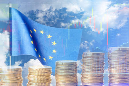 Double exposure of European Union flag against blue sky and coinsの写真素材