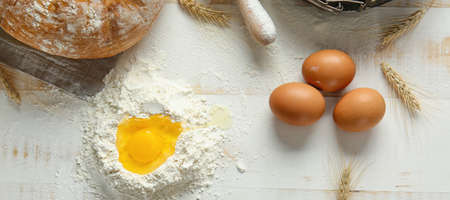 Wheat flour with fresh eggs on white wooden backgroundの写真素材