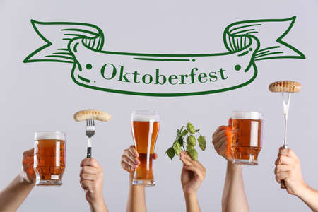 Hands with beer and sausages on gray background. Oktoberfest celebrationの写真素材