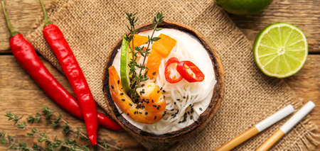 Coconut with tasty Thai soup on wooden tableの写真素材