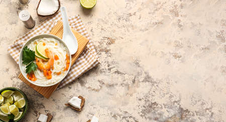 Bowl with tasty Thai soup on grunge background with space for text