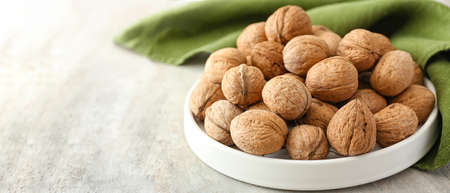 Plate with tasty walnuts on table, closeup