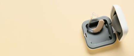 Box with hearing aid on yellow background with space for text